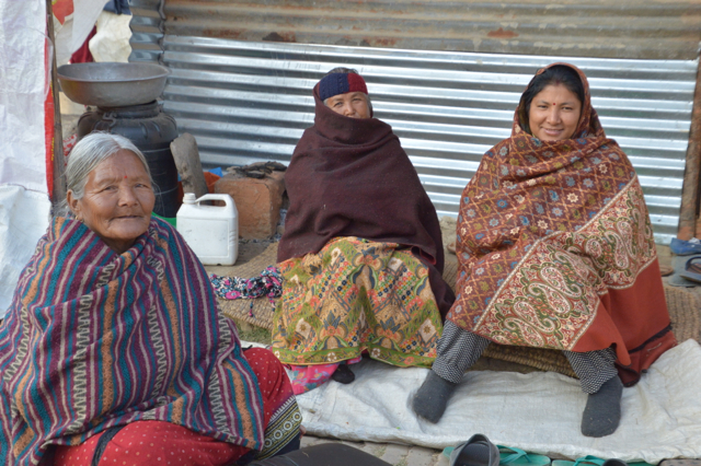 A family who lost their house sits outside their temporary home.